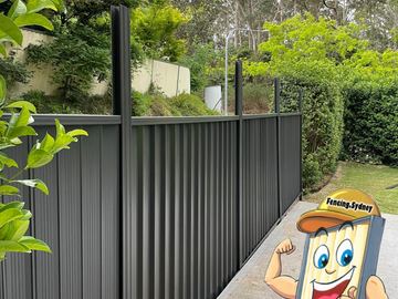 Charcoal Colorbond privacy fence along a paved path with garden planting beside it