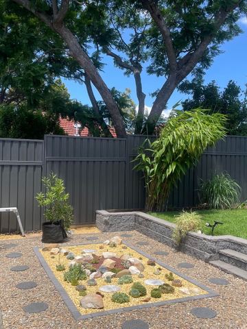 Charcoal Colorbond privacy fence enclosing a gravel courtyard with a small garden bed