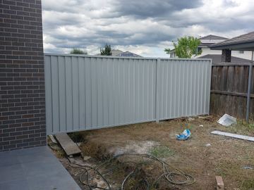 Short run of light grey Colorbond privacy fence on a bare residential yard