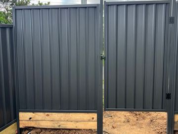 Charcoal Colorbond pedestrian gate with a timber base beside matching fence sheets