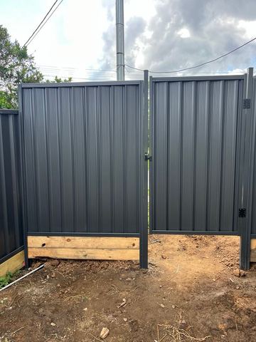 Charcoal Colorbond pedestrian gate with a timber base beside matching fence sheets