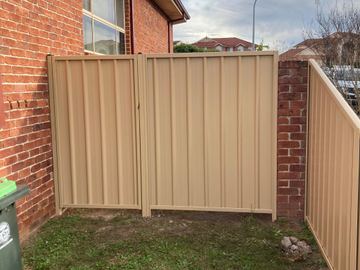 Cream Colorbond double driveway gate set between brick walls