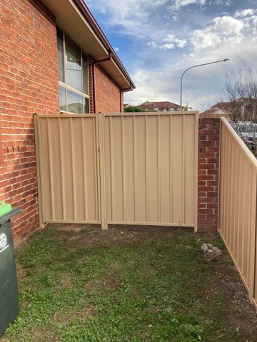 Cream Colorbond double driveway gate set between brick walls
