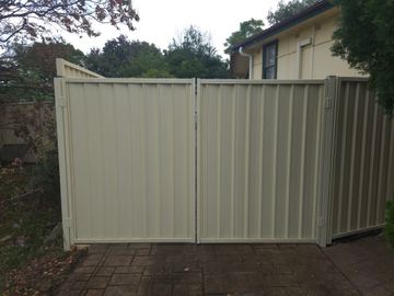 Cream Colorbond double driveway gate facing a residential street