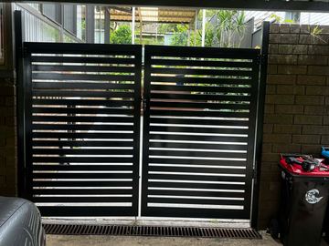 Black aluminium horizontal slat double driveway gate beside a wheelie bin