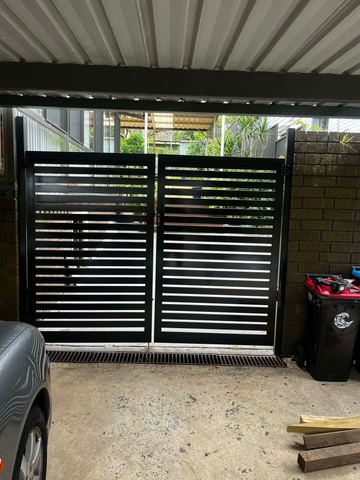 Black aluminium horizontal slat double driveway gate beside a wheelie bin