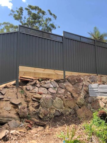 Grey privacy sheets with horizontal louvre blades above a timber sleeper base.
