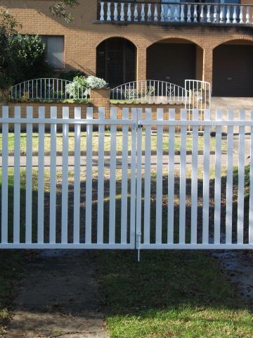 The scene shows a mid grey corrugated steel fence where garden beds sit at the base.