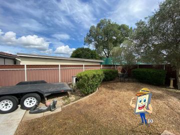 Cream Colorbond privacy fence across a dirt yard with a trailer parked in front