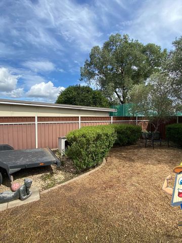 Cream Colorbond privacy fence across a dirt yard with a trailer parked in front