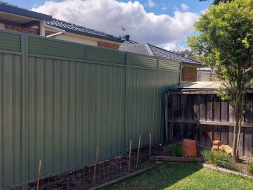Green Colorbond privacy fence with a slat topper along a backyard boundary