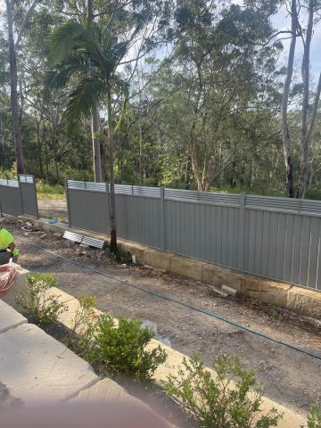 Mid grey Colorbond privacy fence running along a bushland boundary on a dirt yard