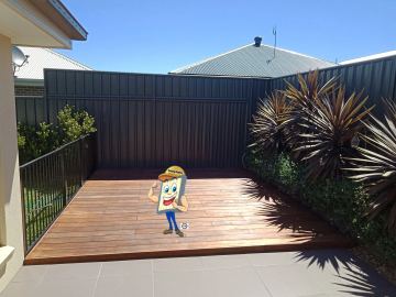 Charcoal Colorbond privacy fence enclosing a timber deck with potted plants
