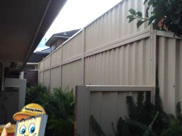 Tall cream stacked panels tower above lush ferns along a side passage beside house eaves.
