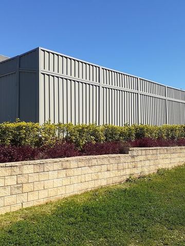 Long charcoal Colorbond fence with a slat height extension on a commercial building