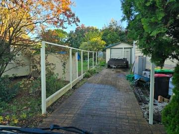 Cream Colorbond posts and rails set along a paved drive toward a garage