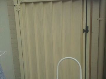 Close view of cream Colorbond sheets and a latch on a matching pedestrian gate