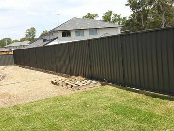 Long dark Colorbond privacy fence across a newly turfed backyard