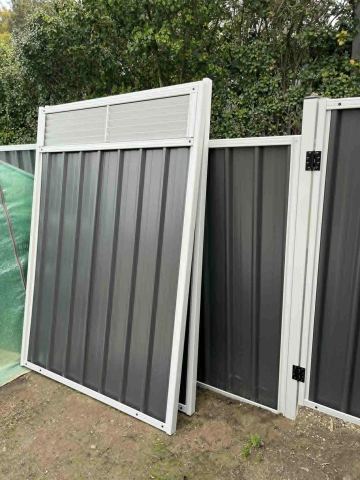 Charcoal ribbed sheets in a light grey frame include a gate with a louvre upper section in a leafy backyard.