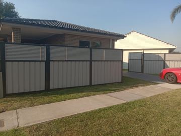 The scene shows a mid grey corrugated steel fence where sleepers form the base.