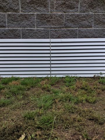 The scene shows a mid grey corrugated steel fence where louvre sections add ventilation, sleepers form the base.