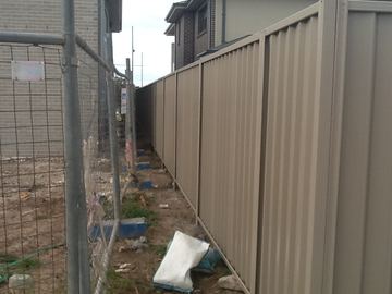 The scene shows a mid grey corrugated steel fence where sleepers form the base.