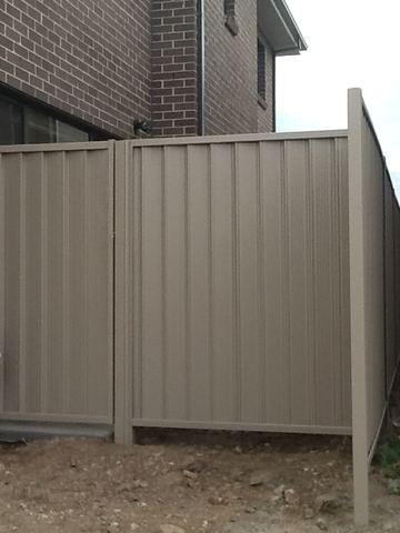 The scene shows a mid grey corrugated steel fence where sleepers form the base.