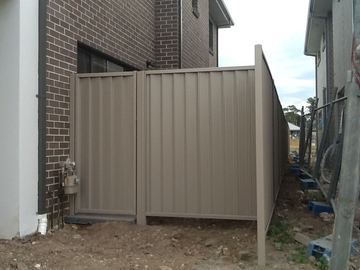 The scene shows a mid grey corrugated steel fence where sleepers form the base.