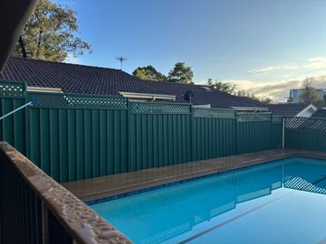 Green Colorbond privacy fence with a lattice topper around a swimming pool