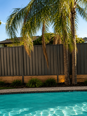 The scene shows a brown corrugated steel fence where sleepers form the base.