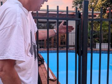 Close view of a black tubular pool fence with a person standing beside it