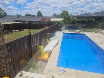 Dark boundary fence enclosing a rectangular backyard swimming pool