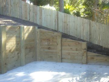 Treated pine paling fence forming a retaining wall around an empty pool