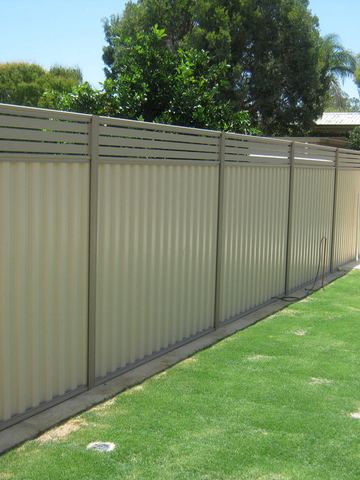 Cream corrugated panels with a grey aluminium slat extension along a lawn beside a pool area.