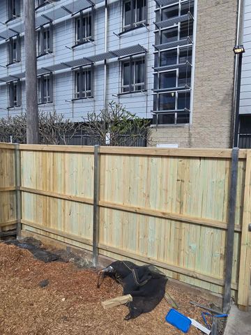 New treated pine palings beside paved areas.