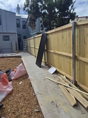 New treated pine palings beside paved areas.