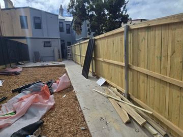 New treated pine palings beside paved areas.