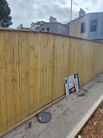 New treated pine palings beside paved areas.