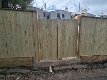 New treated pine palings beside paved areas.