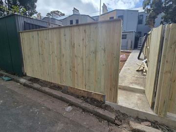 New treated pine palings beside paved areas.