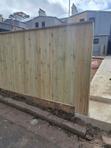 New treated pine palings beside paved areas.