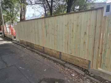 New treated pine palings beside paved areas.
