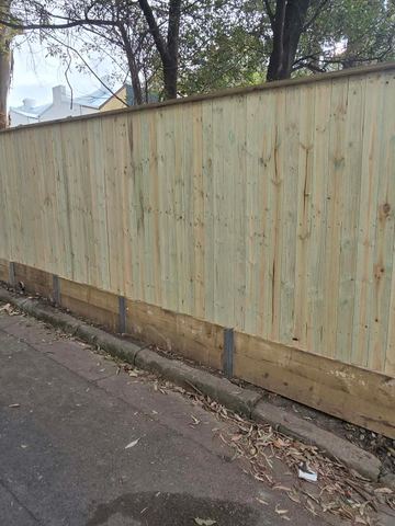 New treated pine palings beside paved areas.