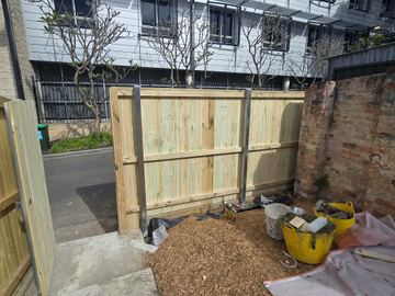 New treated pine palings beside paved areas.