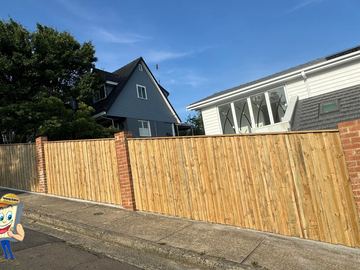 Treated pine paling fence set between brick piers along a street footpath