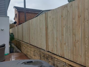 New treated pine palings beside paved areas.