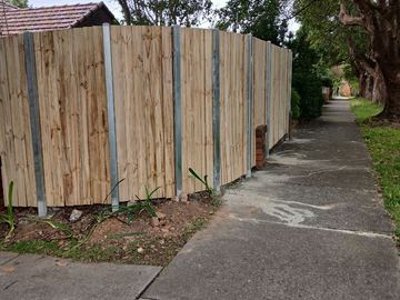 New treated pine palings beside paved areas.