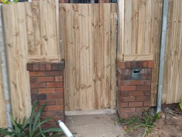 New treated pine palings beside paved areas.
