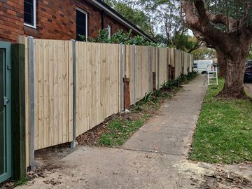 New treated pine palings beside paved areas.