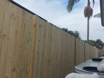 New treated pine palings beside paved areas.